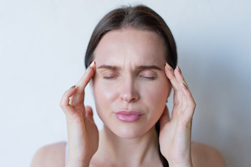 Woman holding her temples experiencing headache and jaw pain